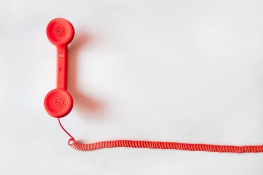 pexels-photo-33999-2 Vintage red phone handset with coiled cable on a clean white background, classic communication device.